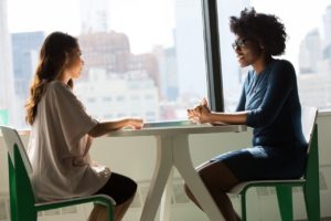 Two women sitting apart from each other across a table.